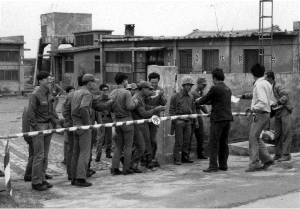1977.11.19蘇東啟穿囚服至雲林沿海的軍營散發選舉傳單，以台灣人為主的充員兵爭睹傳單。（771119N25／施明德提供） 