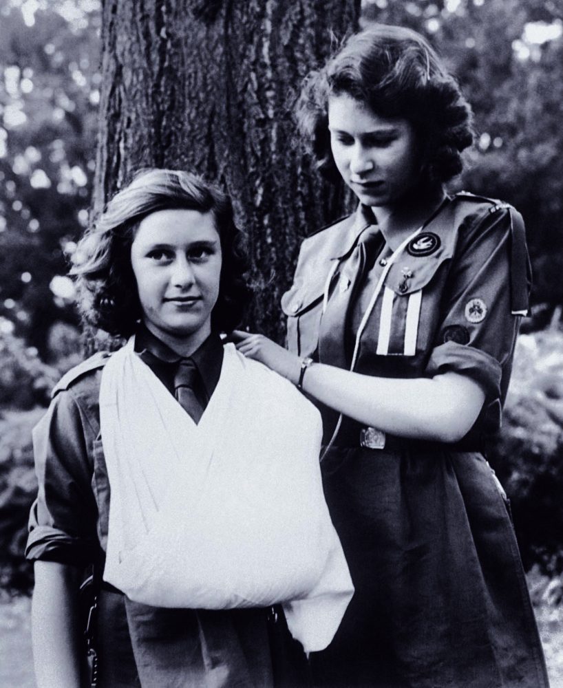 穿著女童軍制服的伊麗莎白（右）和瑪格麗特公主（左），攝於1943年08月，兩人正在練習包紮，從伊麗莎白的穿著可以看出她已經是女童軍的小隊長。圖片來源：美聯社