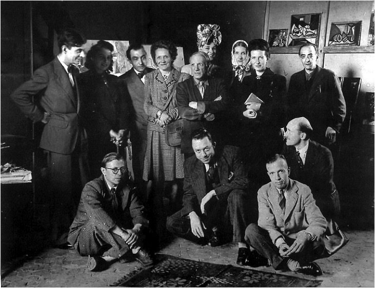 1944年，一群法國知識分子接待畢卡索（Pablo Picasso，1881- 1973）的照片。上排最左邊者是著名的精神分析哲學家拉岡（Jacques Lacan，1901- 1981）。上排左起第二位是深受達達主義與立體派影響的詩人勒維迪（Pierre Reverdy，1889- 1960)。上排右二是西蒙波娃。下排右二是最早對法國前衛派藝術進行評論，並結合人類學的田野調查與超現實主義來譜寫自傳的作家雷希斯（Michel Leiris，1901- 1990）。下排左一是沙特。下排左二是卡繆。 
