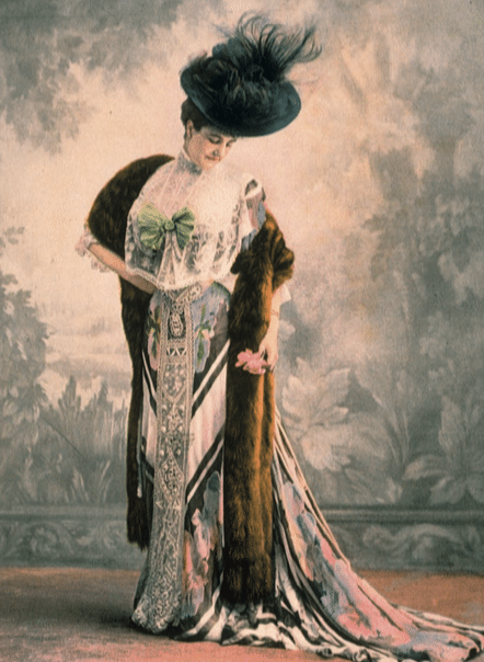 1907年，維爾福特小姐〈Mlle Wilford〉身穿由杜塞時裝屋製作的日禮服。摘錄自《時尚》〈Les Modes〉雜誌 圖中這一襲四月穿的日禮服配上了皮草披肩和羽飾帽子，是由杜塞時裝屋出品。杜塞是巴黎最古老的高級時裝訂製屋，其設計以細緻嬌柔的新藝術美學聞名，因為無法適應講求簡潔流暢的現代風格，最終在1932年歇業。 